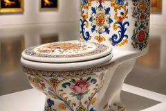 DALL·E-2025-09-02-20.59.43-A-photorealistic-close-up-of-a-white-porcelain-toilet-displayed-as-an-art-piece-in-an-art-gallery.-The-toilets-entire-smooth-surface-is-painted-with-