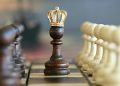 A brown pawn with a crown stands prominently on a chessboard, symbolizing strategic play.