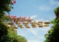 Conical hats strung between trees under a blue sky