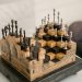 Artistic chess set with 3D pieces on an intricate wooden board indoors.