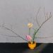 A serene minimalist floral arrangement in a wooden vase with branches and blooms.