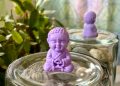 a small buddha statue sitting on top of a jar