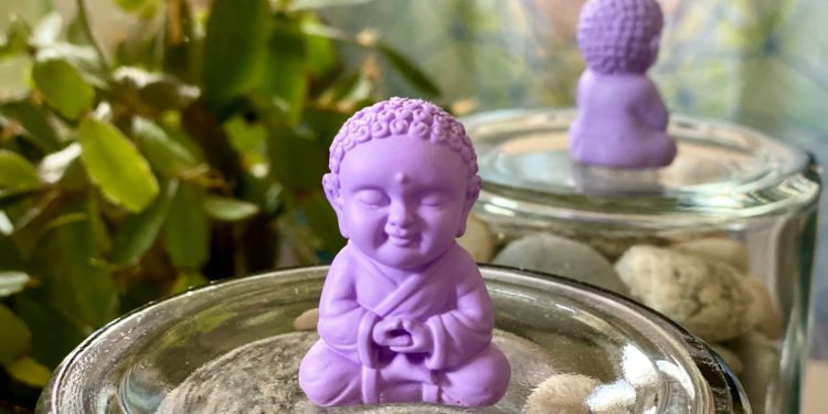 a small buddha statue sitting on top of a jar