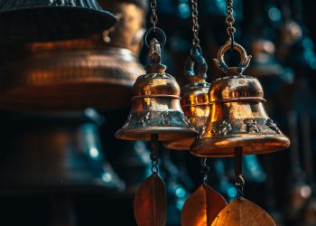 gold bell hanging on brown wooden wall
