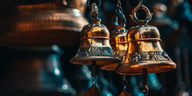 gold bell hanging on brown wooden wall