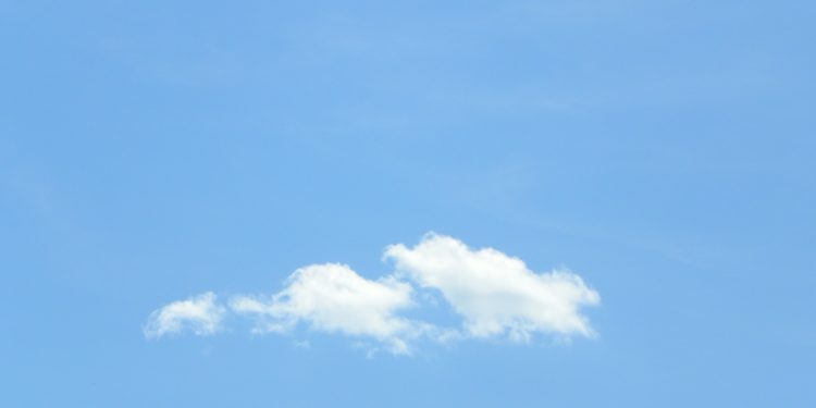 A plane flying in the sky with a cloud in the background