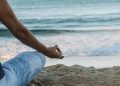 person in blue shorts sitting on beach shore during daytime