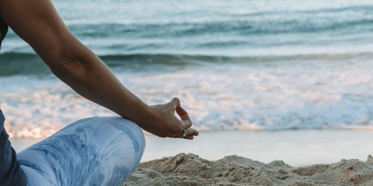 person in blue shorts sitting on beach shore during daytime