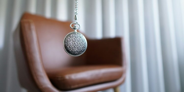 silver round pendant on brown wooden chair