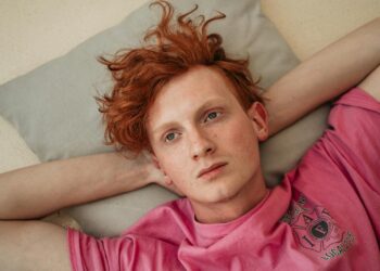Close-up portrait of a man with red hair laying on a pillow indoors.