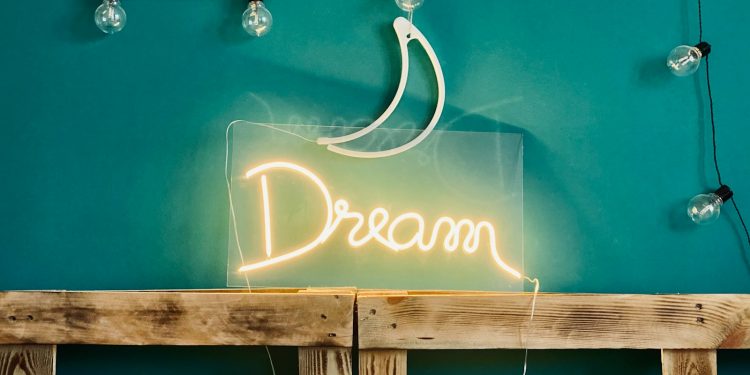 a bed with a neon sign above it