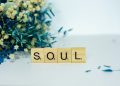a wooden block spelling the word soul next to a bouquet of flowers