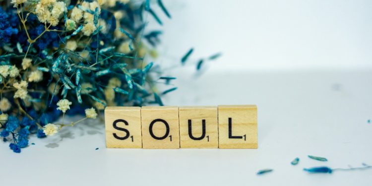 a wooden block spelling the word soul next to a bouquet of flowers