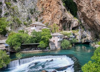 a waterfall and a building by a cliff