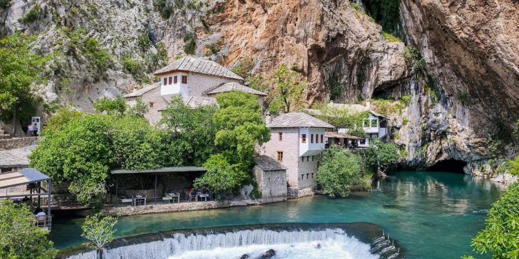 a waterfall and a building by a cliff