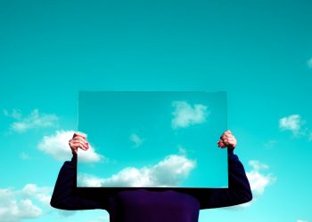 man in black suit jacket raising his right hand