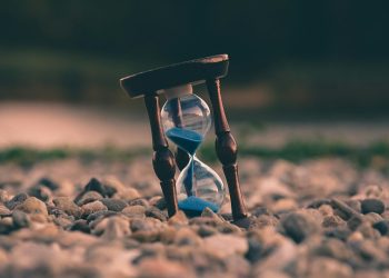 selective focus photo of brown and blue hourglass on stones