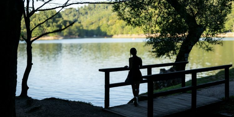 a person sitting on a bench near a body of water