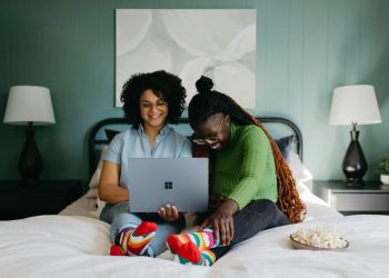 a woman sitting on a bed using a laptop