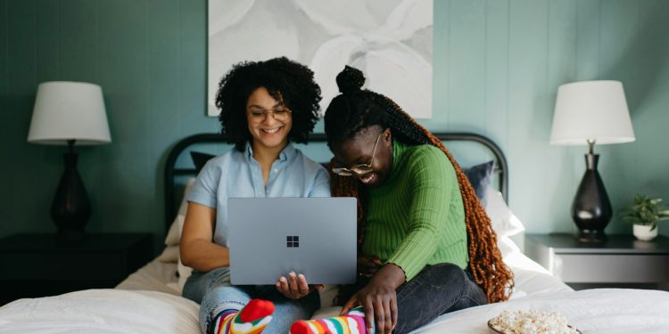 a woman sitting on a bed using a laptop